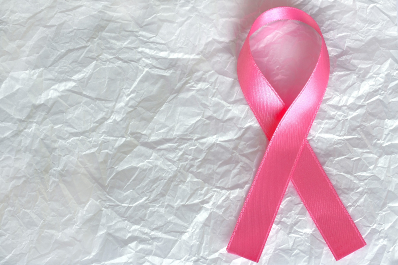 zerknülltes weißes Papier auf der eine pinkfarbenen Schleife liegt als Brustkrebs-Symbol für alle Überlebenden