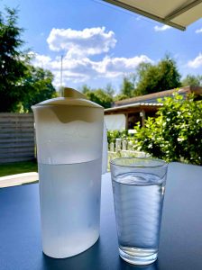Karaffe mit Wasser daneben ein gefülltes Glas